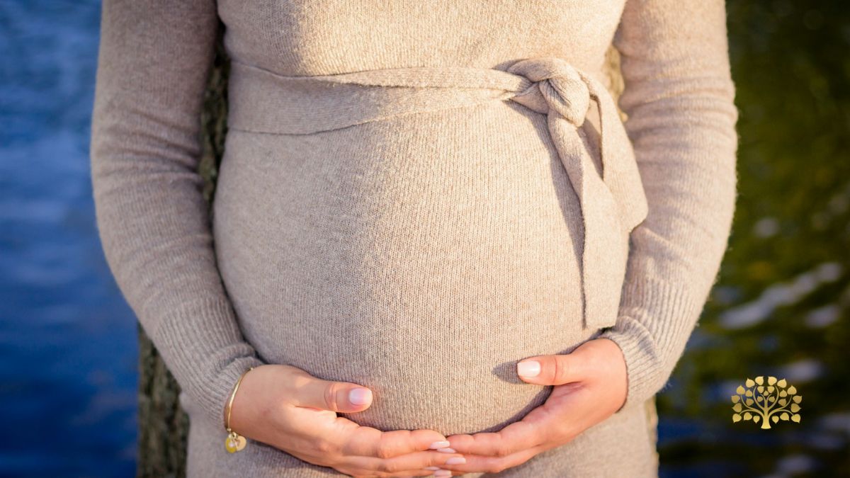 Clare Minter Therapies - Is Maternity Reflexology Safe? image of pregnant lady wearing a beige dressing holding her bump with her hands